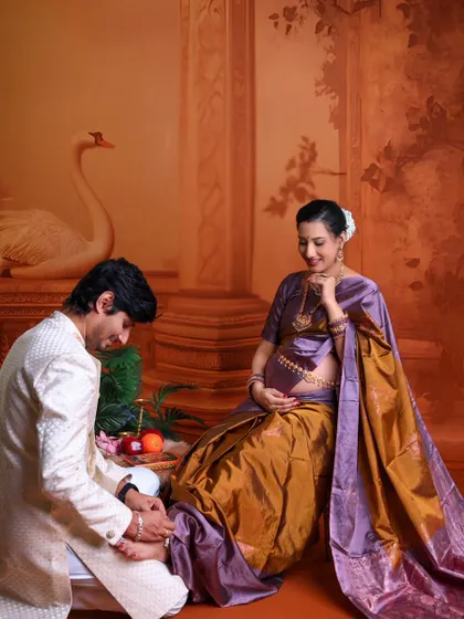 A beautiful moment of care and tradition. The husband-to-be attends to his wife's feet in a gesture of love, set against a traditionally painted backdrop.