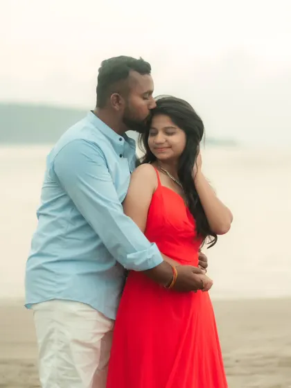 A tender moment on the beach. The groom's casual blue shirt and white pants are a perfect, relaxed complement to the bride's simple red dress.