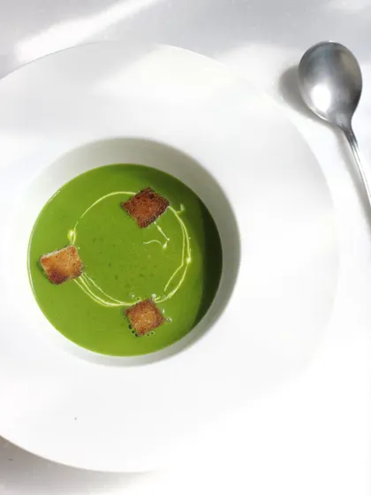 A vibrant green pea soup with croutons. We teach the fundamentals of soup making, from purées and bisques to clear consommés.