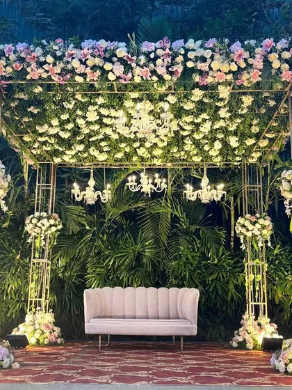 A full view of the floral fairytale stage, perfect for an engagement or reception, with a ceiling of white flowers and sparkling chandeliers.