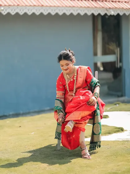 A full-length shot of a happy bride, her intricate mehndi visible as she adjusts her saree. The mehndi is an essential part of her complete bridal look.