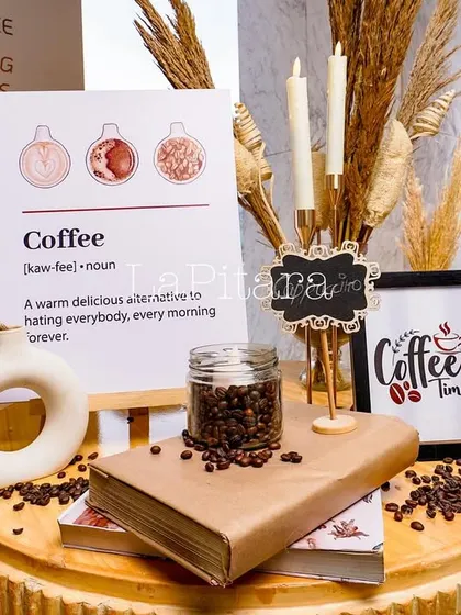 We love adding a touch of humor and personality. This vignette includes a fun sign defining coffee, styled with books, candles, and pampas grass for a cozy, curated corner.