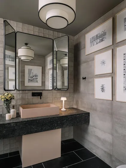 The powder room off the home office lounge is sleek and modern, with a unique three-panel mirror and framed architectural drawings.