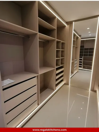 A long, galley-style closet with open shelving and drawers. The integrated strip lighting along the floor and ceiling ensures the entire space is well-lit and easy to navigate.