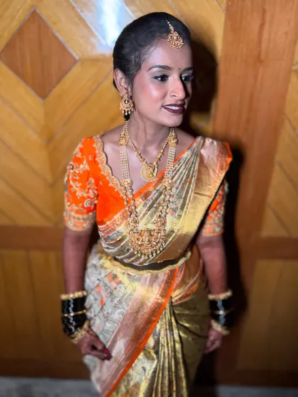 A beautiful profile of a traditional bride. The soft lighting highlights her glowing skin and the intricate details of her gold jewellery and embroidered blouse.