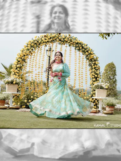 The bride twirling in her Haldi outfit in front of a stunning yellow floral arch.