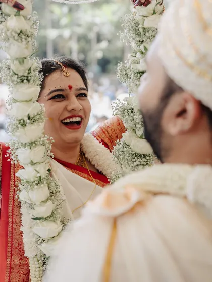 The garland exchange is a moment of pure joy and acceptance. The bride's laughter here is infectious, a beautiful, candid capture from a vibrant Kannadiga and Gujarati wedding.