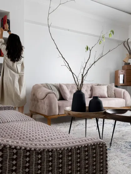 A view of the living space showing the arrangement of furniture, with a person styling the bookshelves in the background. This highlights the lived-in, personal feel we strive to create.