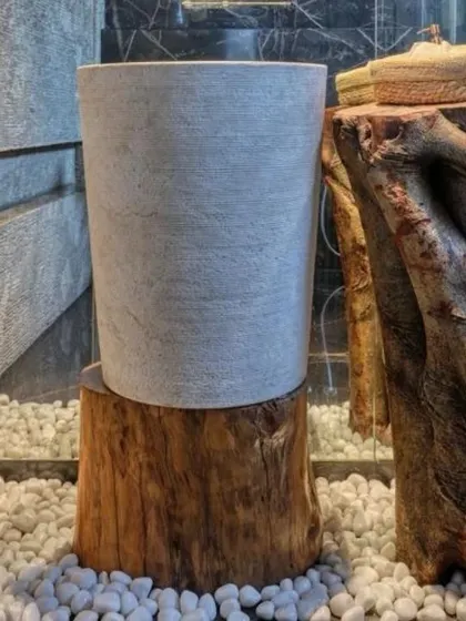A close-up of a washbasin detail that exemplifies my design philosophy. A simple stone basin rests on a raw log, set against a backdrop of split-face stone tiles and reclaimed tree roots. It's a composition that harmonizes natural textures and forms.
