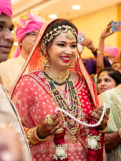The bride, surrounded by her parents, smiles happily during a wedding ritual. Capturing family emotions is central to our work.