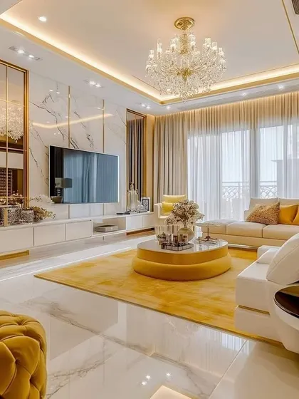 A glamorous living room featuring a marble accent wall, gold trim, and a stunning crystal chandelier. The yellow and white color scheme creates a bright, opulent space perfect for hosting.