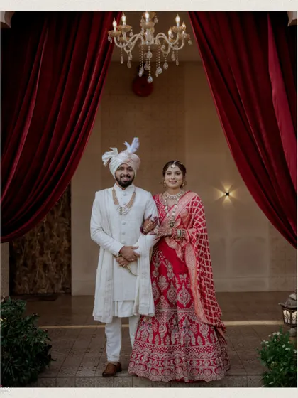 A timeless and formal portrait of the couple, perfectly framed by an archway and red curtains.