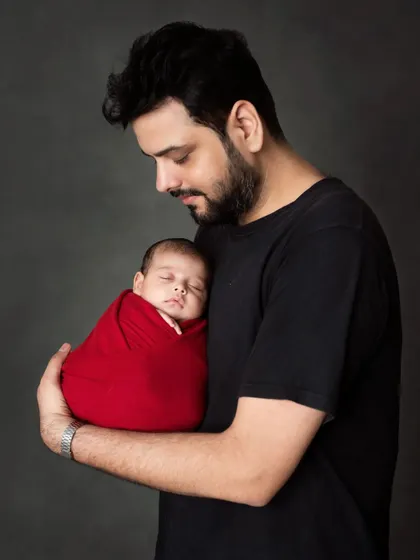 A proud father holds his newborn son, a simple and powerful portrait of new fatherhood.