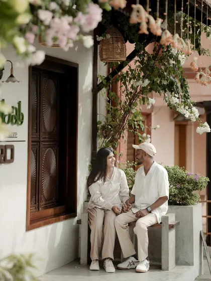 The couple shares a quiet moment on a bench, framed by beautiful flowering branches, creating a serene and romantic scene.