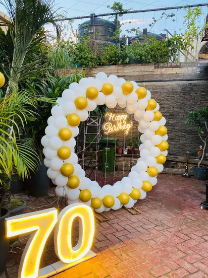 A 70th birthday celebration with a simple yet elegant white and yellow balloon ring and marquee numbers.