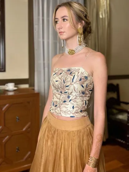 This profile view highlights the intricate braided details in her updo, a perfect choice to complement her modern strapless top and traditional jewelry.