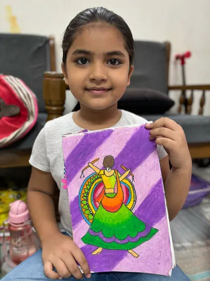 A student holds her beautiful drawing of a garba dancer, capturing the movement and vibrant colours of Navratri.