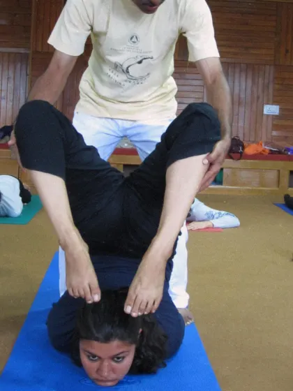 A student receives assistance in a deep flexibility posture during a past TTC. This shows our commitment to helping each student explore their potential safely.