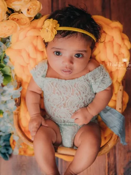 This little girl is perfectly posed in her basket, surrounded by a beautiful arrangement of yellow and blue flowers for her 3-month photoshoot.