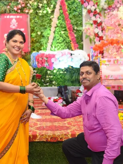 A romantic and playful moment as a man kneels to offer a rose to his wife during the celebration.
