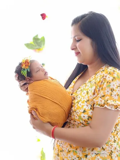 A mother's gentle hold. This bright, beautiful portrait captures the pride and happiness of a new mom with her baby, surrounded by a light floral theme.
