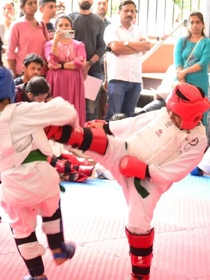 This action shot from a tournament captures the dynamic nature of kumite. Our student lands a controlled kick, showcasing the agility and precision we develop in our training programs.