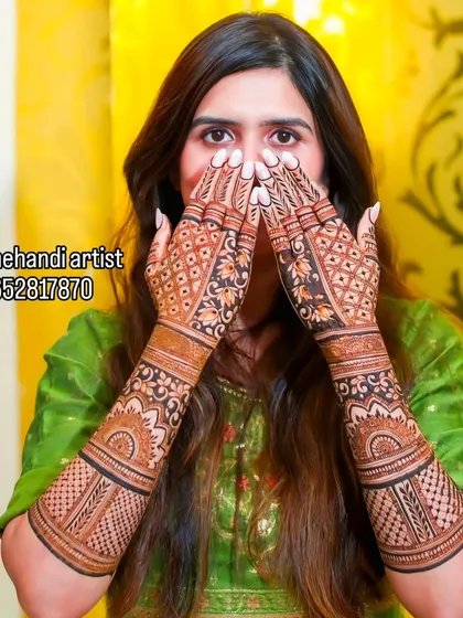 A classic bridal pose showing off the intricate jaali (net) work on the fingers and floral patterns on the arms. This is a popular and elegant choice for brides.