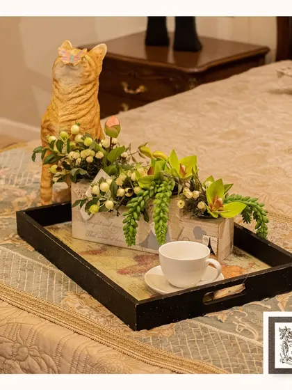 A charming breakfast-in-bed scene featuring a vintage-inspired serving tray. The tray's map-print base adds a touch of worldly character to this cozy and elegant bedroom moment.