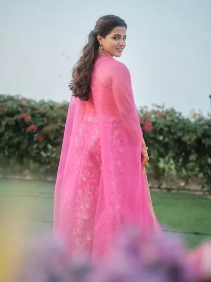 A beautiful shot of the bride in her vibrant pink outfit. The makeup is minimal and fresh, allowing her natural beauty and the stunning color of her lehenga to shine.