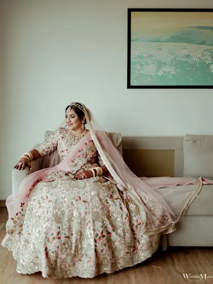 A full-length portrait of the bride, Riddhi, looking regal and serene as she sits ready for her wedding.