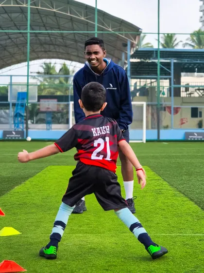 A moment of encouragement between a coach and a young player during a training session on our turf.