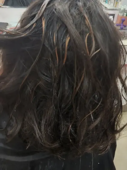 This image shows the "during" phase of a highlight service. The fine strands of hair are carefully selected to create a natural and blended effect once the colour is applied.