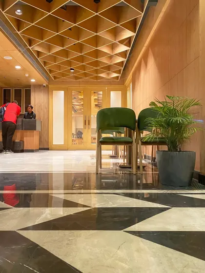 A low-angle shot of the Bhopal hotel's reception area, highlighting the bold geometric floor pattern and the rich texture of the wooden ceiling, demonstrating our focus on every surface.