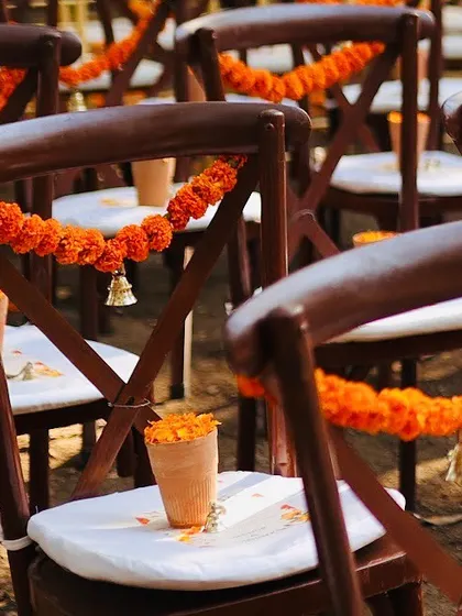 For a traditional wedding with a modern twist, I decorated the guest chairs with marigold garlands and a tiny brass bell. These small touches add to the overall theme and create a delightful visual consistency.
