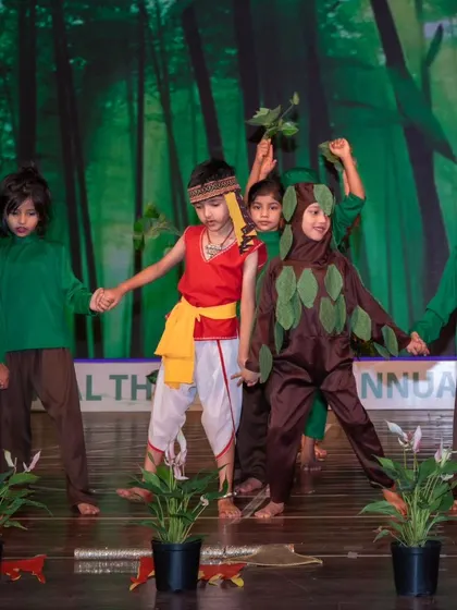 On stage, children dressed as trees and animals perform a play about nature, advocating for our planet.