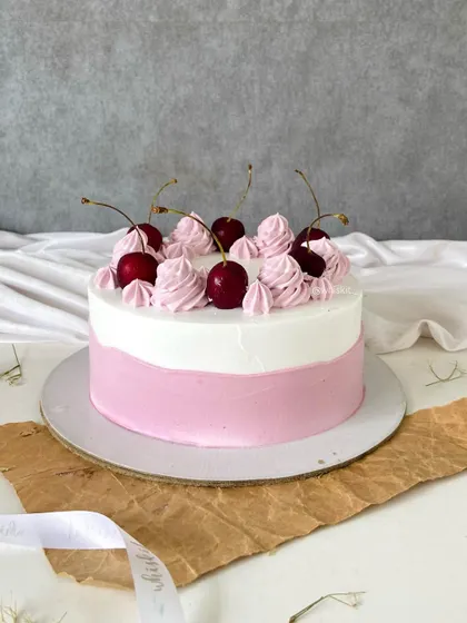 Sometimes, simplicity is key. This cake features a clean pink and white design, topped with fresh, juicy cherries for a classic and delicious look.