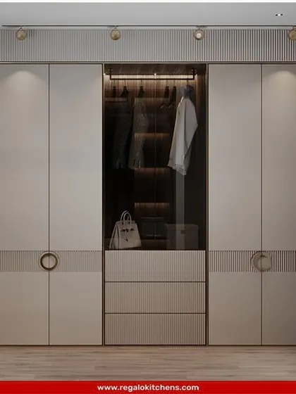 This elegant wardrobe features fluted details and chic circular handles. The central glass display with interior lighting is perfect for showcasing handbags or other prized accessories.