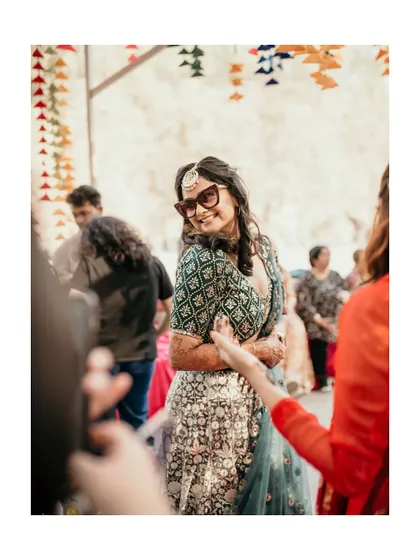 A candid shot of the bride enjoying the dance floor at her mehndi party. Her stylish sunglasses and happy expression capture the fun vibe of the day.