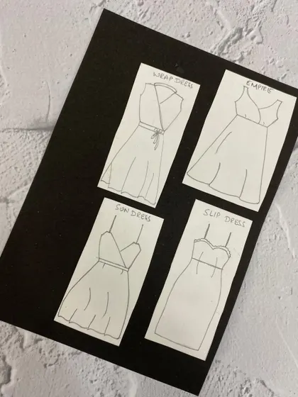 A board showing flat sketches of various dress styles like wrap, empire, and slip dresses.