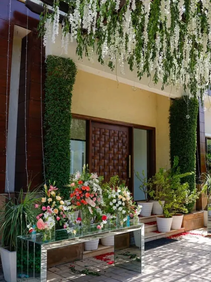 The entrance decor for the Sukhmani Sahib Path, featuring hanging white wisteria and a mirrored table with fresh floral bouquets. This created a welcoming and elegant first impression for guests arriving for the ceremony.