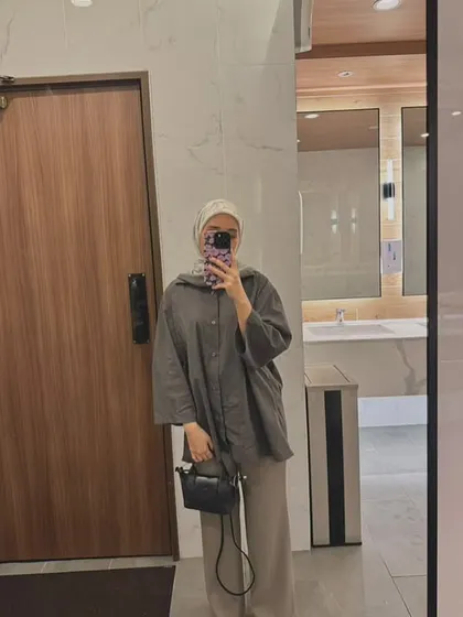 A customer's mirror selfie showing her styling the black Metro Mini bag. It's the perfect size for a minimalist look while still being practical.