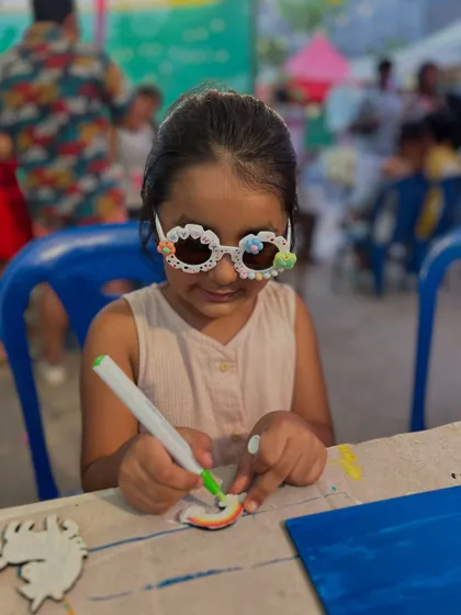This little creator is adding the finishing touches to her artwork, looking super stylish in her decorated sunglasses.