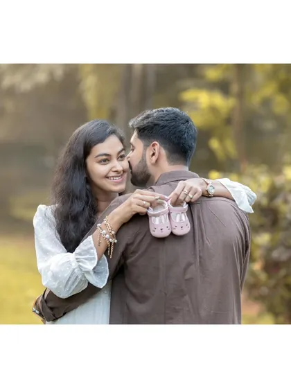 This is the moment it all becomes real. Here, the expecting mother shares a happy, knowing smile with her partner while holding up a tiny pair of baby shoes, a beautiful symbol of the little one they are eagerly awaiting.