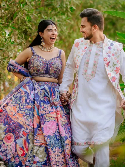 A candid photo of the couple walking and laughing, showcasing their colorful and unique Mehendi outfits.