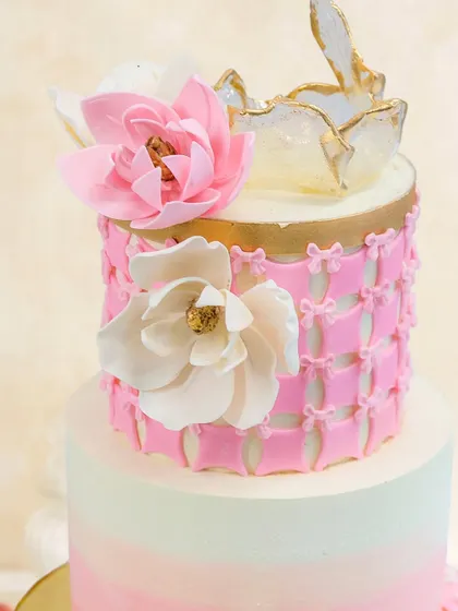 Blush and Frost. A dreamy two-tiered cake with a pink ombre effect, a delicate lattice pattern, and beautiful sugar flowers.