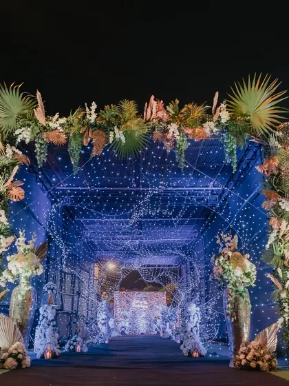 A stunning entrance tunnel for a grand sangeet. We used thousands of fairy lights and lush foliage to create this magical, starlit walkway, setting a glamorous tone for the evening.
