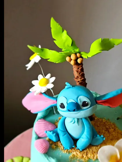 A close-up of the handcrafted Stitch figurine from the Hawaiian-themed cake. You can see the character's personality captured in his expression and posture.