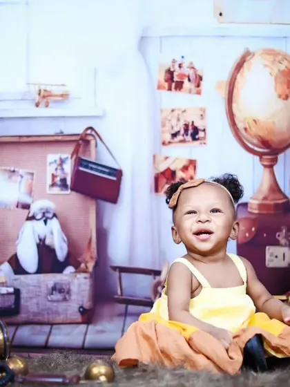 A happy baby girl in a yellow dress enjoying the vintage traveler themed set.