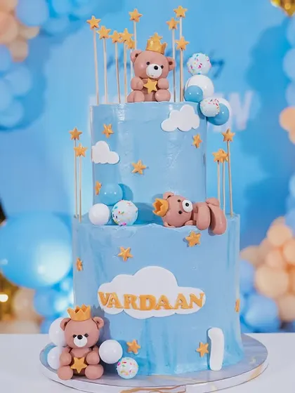 A dreamy three-tiered cake for a teddy bear themed first birthday. Adorned with cute, crowned teddy bears and stars against a soft blue frosting, this cake is as sweet as the occasion.