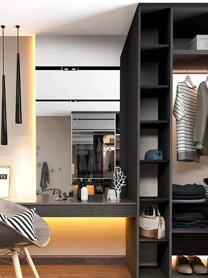 This open-concept closet is integrated with a study or vanity desk. The dark wood and black pendant lights create a chic and modern look, perfect for a studio apartment or master bedroom.